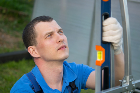 The worker measures the tool, the level of the slope of the metal profile, close-up