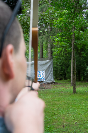 The man pulls the bow string and takes aim at the targetの写真素材