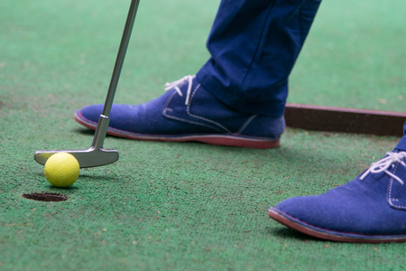 close-up, top view on grass background, mini golf ball and blue shoes