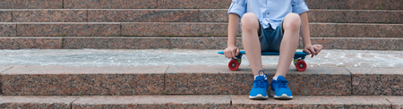 the boy sits on a background of a stone staircase on a sports board, to the left there is a place for an inscriptionの写真素材