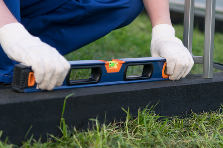 The hands hold a tool to measure the level of the foundation