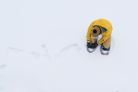 background, top view, man in the snow in a yellow jacket, wearing snowshoes to survive and pass onの写真素材