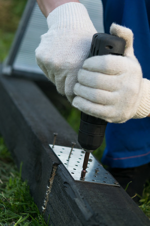 hands holding a screwdriver and fastens the iron plate with screwsの写真素材