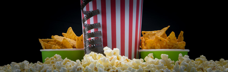 background - appetizer for a cinema, popcorn and two buckets of nachos, backlit, on a black backgroundの写真素材