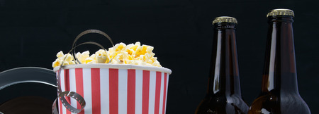 film in popcorn, on a black background, with two bottles of beerの写真素材