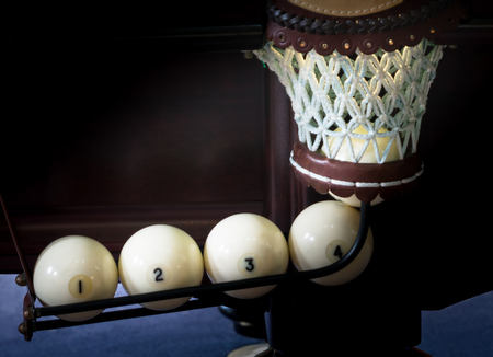 five white billiards balls scored in the hole, the light in the hole, the background close-up