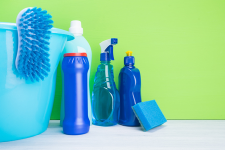 bucket with different bottles of detergents for cleaning on a green backgroundの写真素材