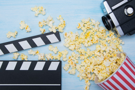double for cinema, old video camera and a glass of scattered popcorn, on a light backgroundの写真素材