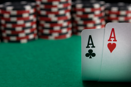 two aces are highlighted against a green table and colored betting chips