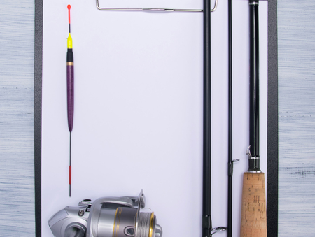 background for recording, the white sheet on the tablet lies on a wooden antique surface, with a set of items for sport fishing, floats, fishing rods and fishing lineの写真素材