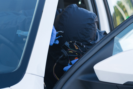 the thief disables the electronic alarm system of the car in the cabin before theft close-upの写真素材
