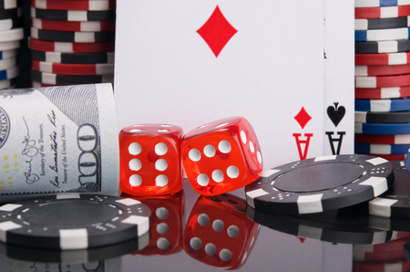 two red dice, surrounded by a gambling set of dollars, cards, casino chips, on a black backgroundの写真素材