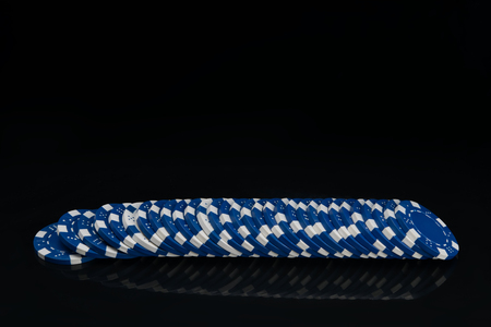 on a black background, with a reflection in a row laid out blue chips for gamblingの写真素材