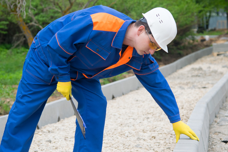 master in blue uniform, takes the amount of work done to install curbs in the Park, in the construction of the roadの写真素材