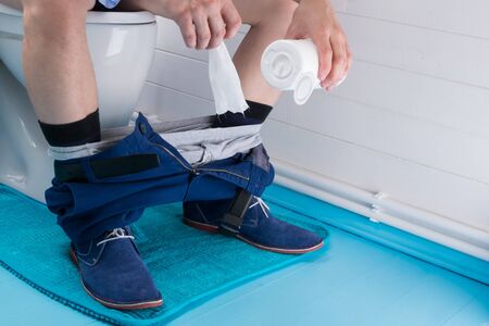 a man is sitting in the toilet and is going to wipe his ass with wet wipes