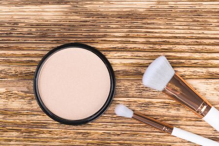 powder to equalize the tone of the face and two brushes lie on a burnt wooden backgroundの写真素材