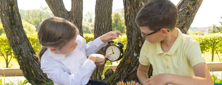in the park, in the fresh air, the girl shows the boy time on the clock so as not to be late for the lessonの写真素材