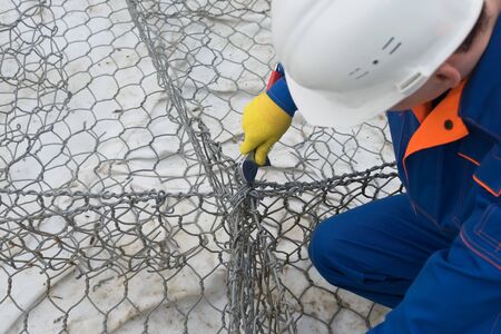 worker's hands knit soft wire construction, close-up