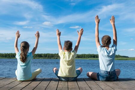 children on the lake doing yoga in good weatherの写真素材
