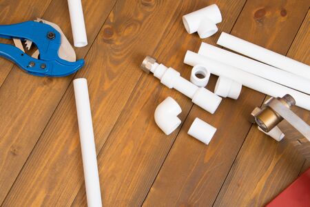on a dark wooden background, blue scissors for cutting white plastic pipes for plumbingの写真素材