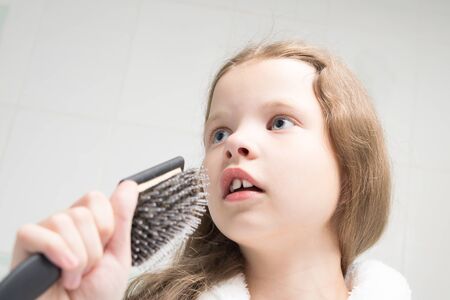 little girl holds a comb in her hand, like a microphone and sings in the bathroom