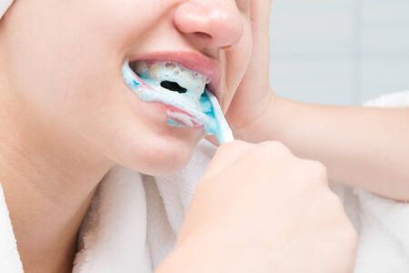 close-up of face and hands with teeth cleaning toothbrushの写真素材