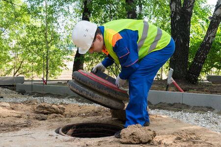 the worker opened the plastic cover of the hatch of urban communications