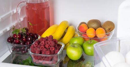 close-up, on the shelf of a white fridge, fresh fruit, berries and a jug with compoteの写真素材