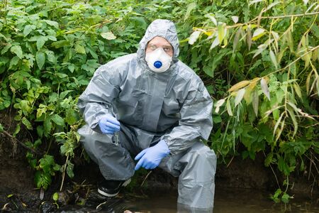 a man in a protective suit against microbes took a sample of water in a flask