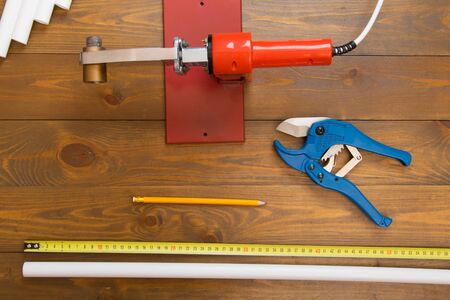 on a dark wooden background, a set of polypropylene pipes, cutting shears and tools for soldering...