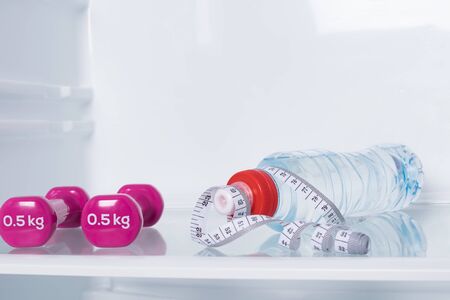 diet concept: dumbbell, bottle of water and measuring tape