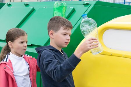 boy and girl throw out plastic trash in a special container on the street, sorting garbageの写真素材