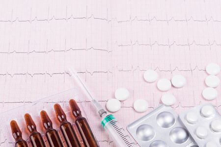 concept of medical drugs and protective agents against coronavirus on the background of a cardiogram...