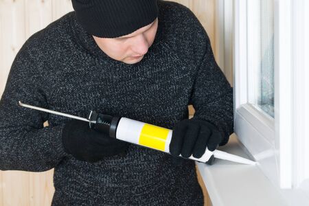 close-up, worker, with a gun, closes the cracks for sealing with foamの写真素材