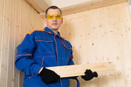 master in blue special clothes holds a wooden board in his hands and looks at the camera