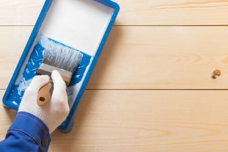 blue bath with impregnation for wood and the hand of a master with a brush in a glove, there is a place for inscriptionの写真素材