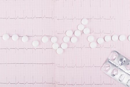 paper with heartbeat readings with white tablets, close-up background, top viewの写真素材