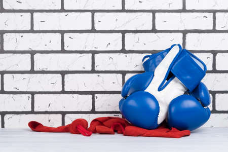 blue boxing gloves lie on red protective bandages on a white brick backgroundの写真素材
