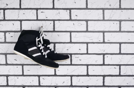 on the background of a brick wall black wrestling shoes, on the right there is a place for inscriptionの写真素材