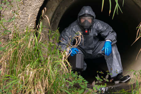 man in protective suit and mask crawls out of the sewer after research, front view