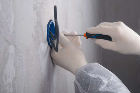 close-up, installation of a glass under an electric socket with two bare wires, hands of the master...