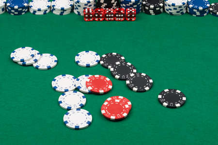 chips and dice are scattered on the green cloth of the poker table, background close-up