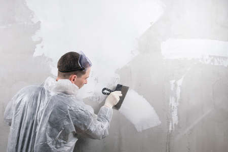 a repairman applies the mixture to the wall to level itの写真素材