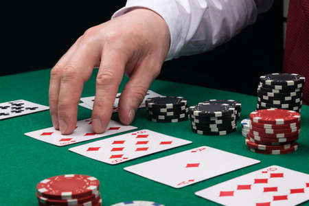 the dealer's hand opens the cards on the green cloth of the poker table, side view