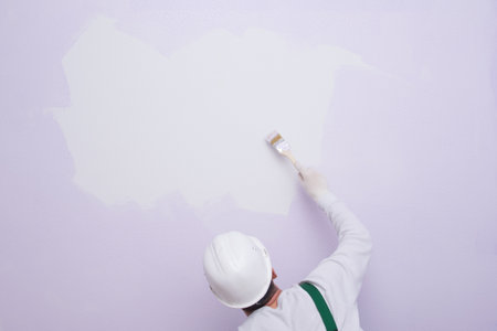 a worker with a brush in his hand, wants to make a drawing on a white space in the wallの写真素材