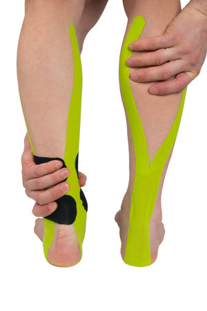 two legs on a white background with glued tapes, a hand pressing the calf muscle in severe pain, close-upの写真素材