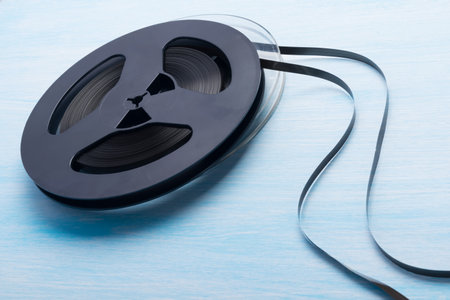 two musical reels with unwound magnetic film, on a blue table background