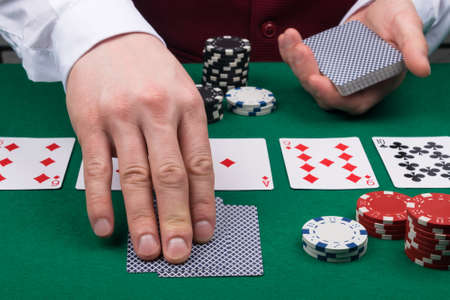 the dealer at the green poker table deals cards to the playerの写真素材