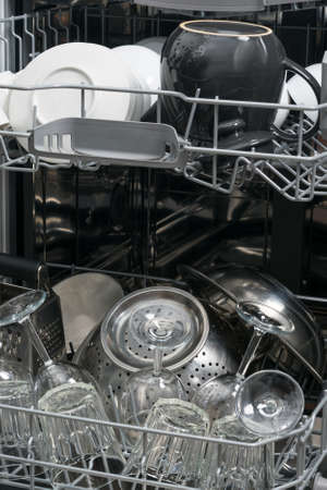 a stack of dirty dishes stands on the door of the dishwasher, front viewの写真素材