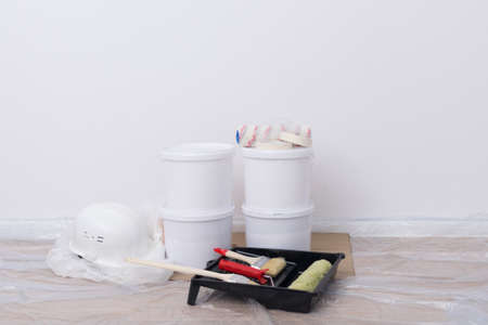 a set of building materials, buckets of paint, protective clothing and a helmet on a white wall backgroundの写真素材